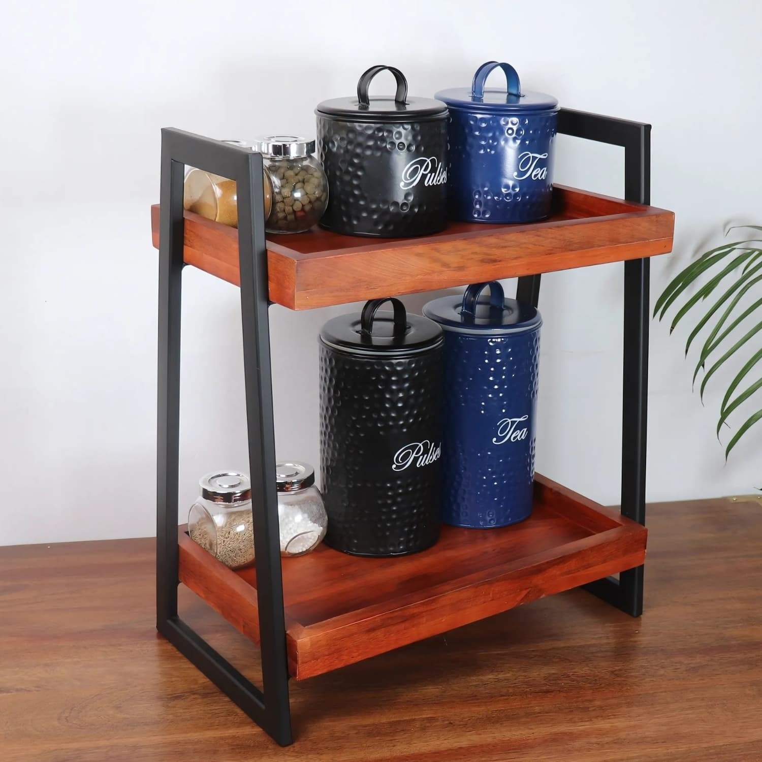 Loosebucket Linea Premium Wooden Kitchen Organizer featuring two-tier walnut-finished acacia wood shelves with black metal frame, displaying decorative black and blue storage canisters for tea, pulse and spices. Modern rustic design perfect for kitchen storage and organization.