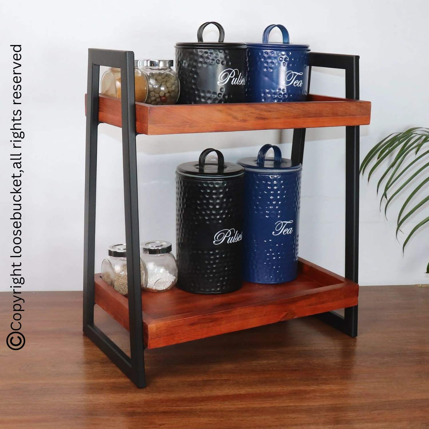 Loosebucket Linea Premium Wooden Kitchen Organizer featuring two-tier walnut-finished acacia wood shelves with black metal frame, displaying decorative storage containers in black and navy blue with glass jars. Perfect for kitchen organization and storage.